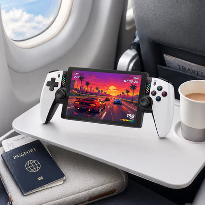 iGameConsole M28 Titan portable gaming console on an airplane tray table with coffee and travel essentials, highlighting gaming on the go with a compact handheld design.