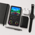 iGameConsole R36T MAX carbon fiber black compact retro handheld console beside everyday carry items including a notebook, pen, earbuds case, wallet, and watch, showing portable size and daily carry convenience.