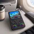 iGameConsole R36T MAX carbon fiber black portable gaming console on an airplane tray table with a coffee cup and travel pouch, showing retro gaming on the go.
