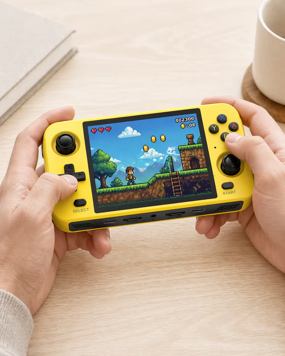 Adult hands holding the iGameConsole R40S bright yellow portable handheld console, showing its compact horizontal design, dual joysticks, D-pad, colorful ABXY buttons, and retro platform game screen.