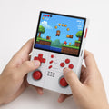 Adult hands holding the iGameConsole R40XX Pro Max white and red portable handheld console, showing its compact size, comfortable grip, vertical layout, dual joysticks, red D-pad, and retro platform game screen.