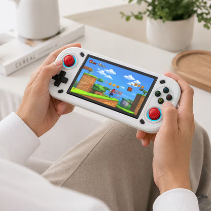 Adult hands holding the iGameConsole R43S white portable handheld console, showing its compact horizontal design, dual red joysticks, black D-pad, colorful ABXY buttons, and retro game screen.