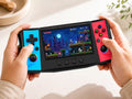 Adult hands holding the iGameConsole R50 Ultra black portable handheld console with cyan and red side panels, showing its compact horizontal design, comfortable grip, dual RGB-ring joysticks, D-pad, and retro pixel game screen.