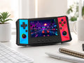 iGameConsole R50 Ultra black retro portable console with cyan and red side panels on a clean modern desk setup with a keyboard, notebook, coffee mug, plant, and a retro racing game screen.