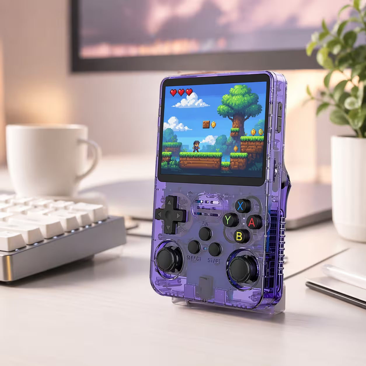 iGameConsole retro portable gaming console on a clean modern desk setup with keyboard, coffee, plant, and a colorful pixel game screen.