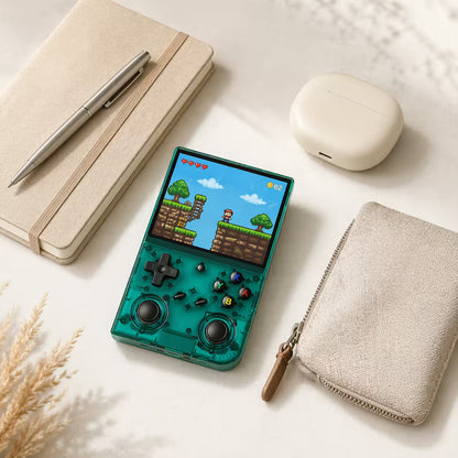 iGameConsole RG35XX Pro transparent teal compact retro handheld console beside everyday carry items including a notebook, pen, earbuds case, pouch, and minimalist desk accessories, showing portable size and retro gaming style.