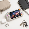 iGameConsole RG52 Pro Max off-white and orange compact retro handheld console beside everyday carry items including a notebook, pen, earbuds case, and pouch, showing portable size and daily carry convenience.