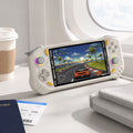 iGameConsole RG52 Pro Max off-white and orange portable gaming console on an airplane tray table with a coffee cup and travel pouch, showing gaming on the go.