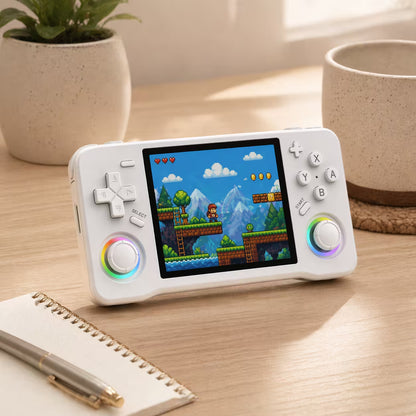 iGameConsole XF35H white retro portable console on a clean modern desk setup with a notebook, coffee mug, plant, and colorful pixel game screen.
