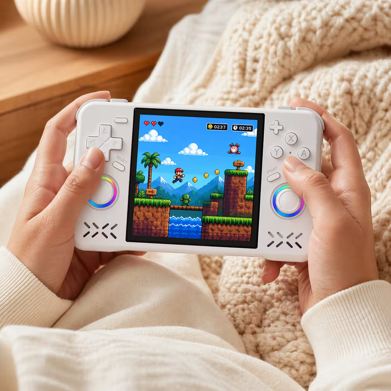 Adult hands holding the iGameConsole XF40H WiFi Pro white portable handheld console, showing its compact horizontal design, comfortable grip, dual RGB-ring joysticks, D-pad, and retro platform game screen.