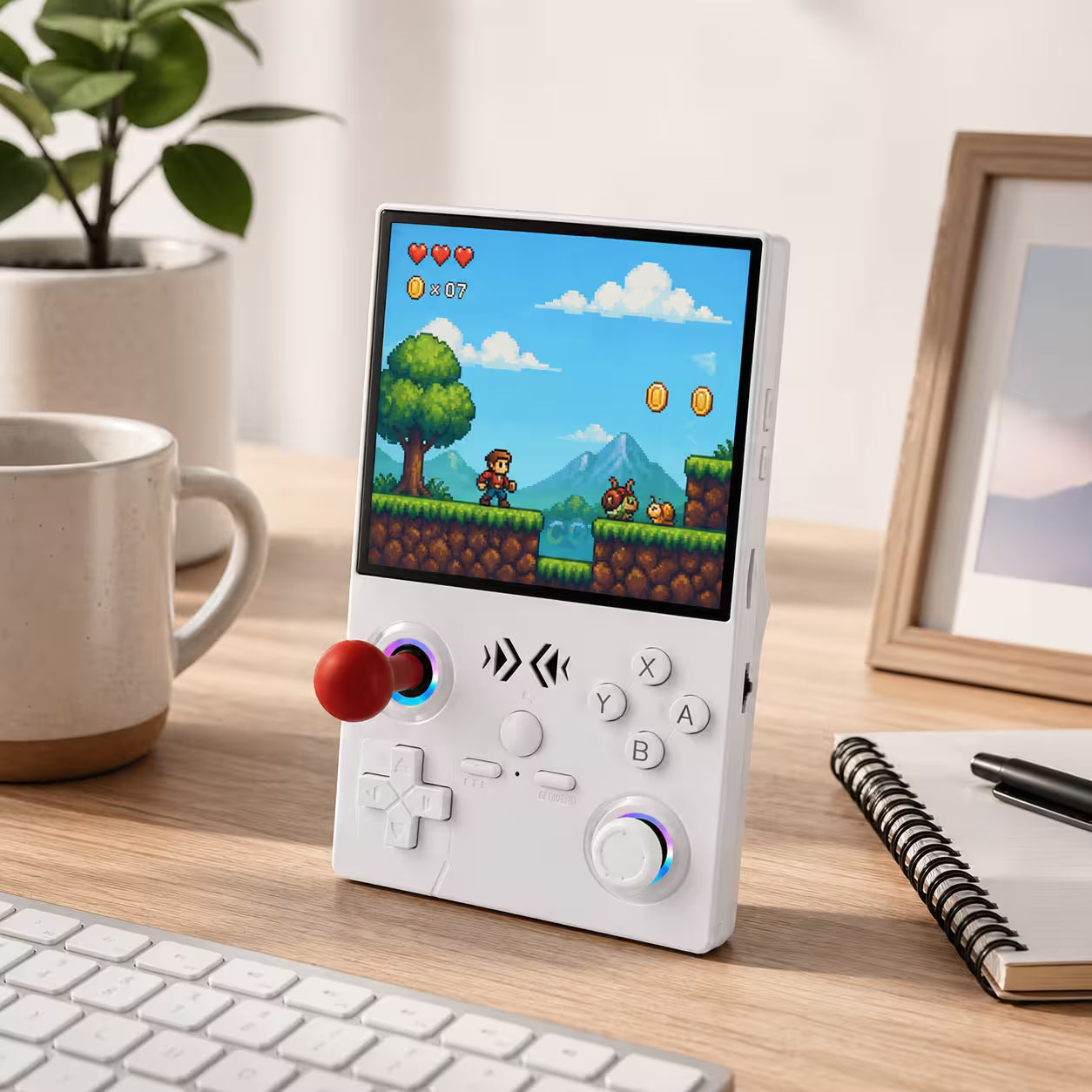 iGameConsole XF40V white retro portable gaming console on a clean modern desk setup with a plant, coffee mug, notebook, keyboard, and colorful pixel game screen.